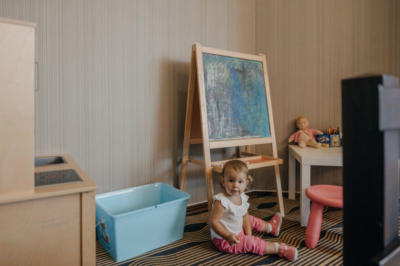 A toddler playing in the kids' corner by the chalkboard and toy kitchen