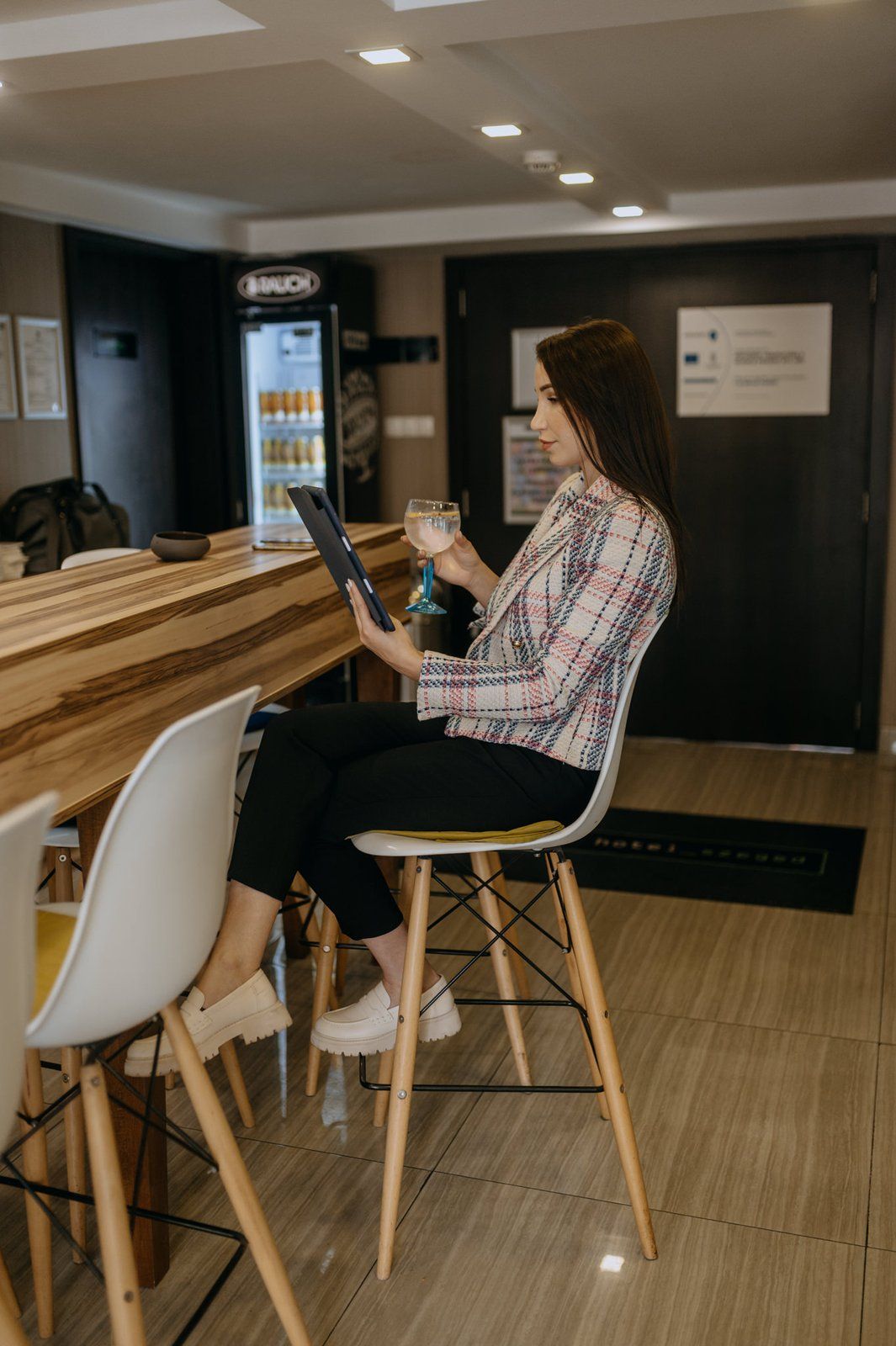 A guest sitting alone at the bar with a tablet and a drink