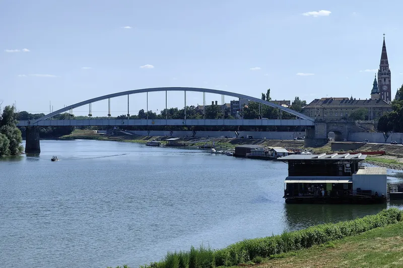 Tisa, podul din centru și turnul catedralei în soare, văzute de pe malul din Újszeged