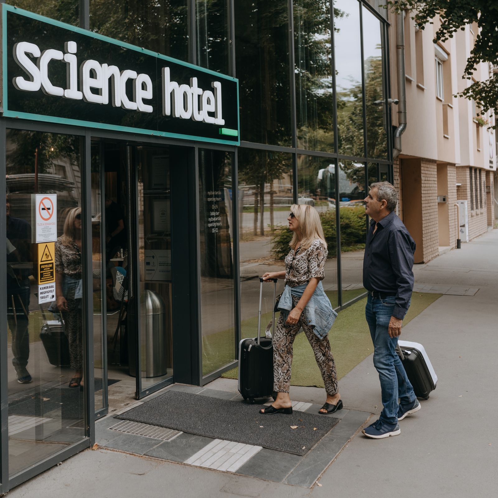 Pár bőröndökkel érkezik a Science Hotel bejáratához