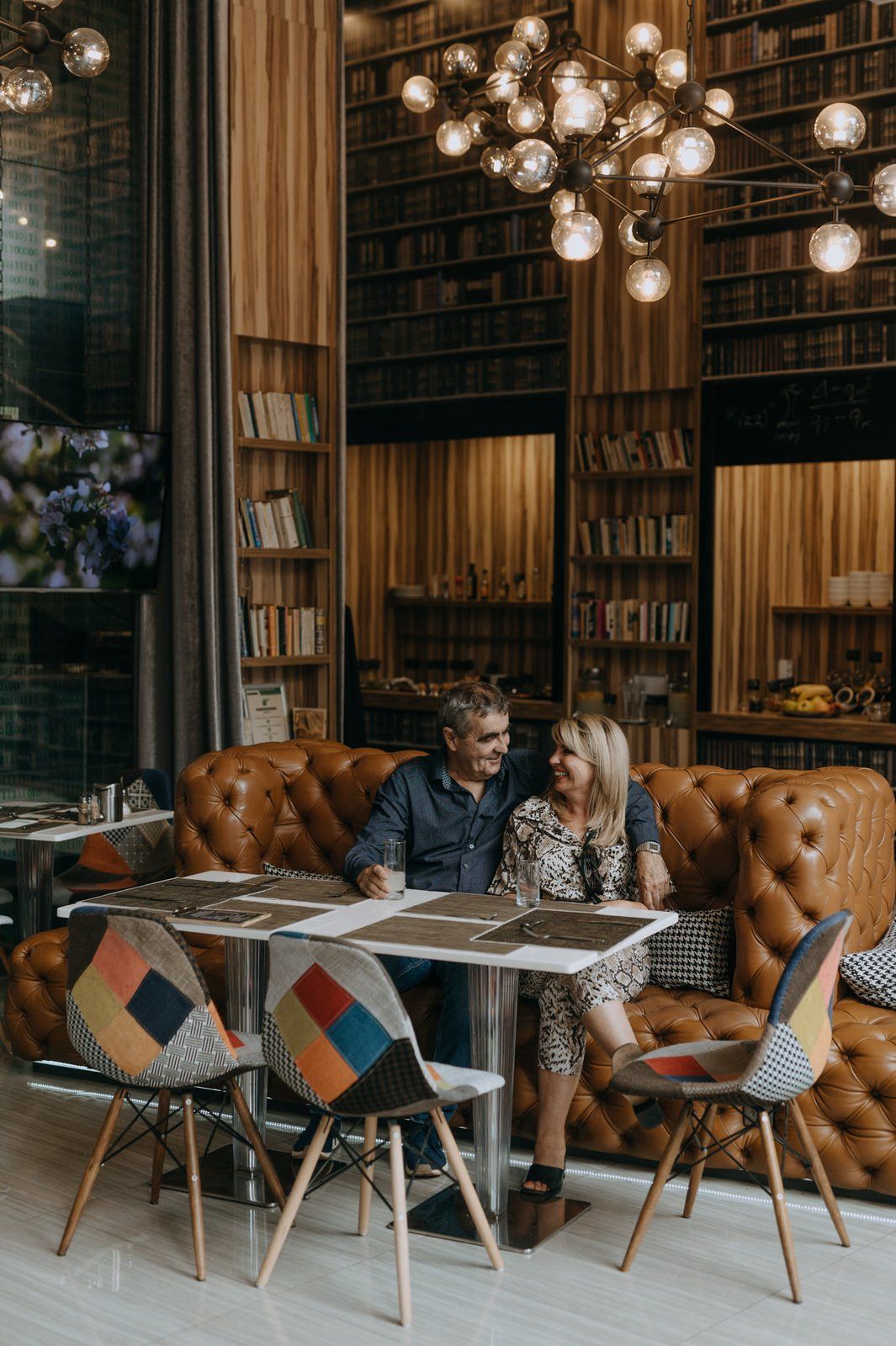Könyvtárfalas lounge bőrkanapéval és gömbös csillárral